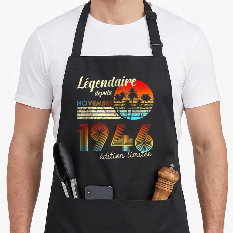 Tablier de cuisine noir avec motif rétro soleil couchant palmiers et texte « Légendaire depuis 1946 »