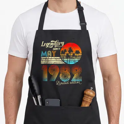 Tablier de cuisine noir avec illustration rétro palmiers et texte Legendary Since Mai 1982 Limited edition