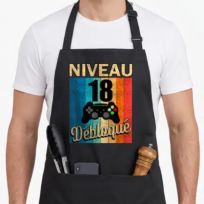 Tablier de cuisine noir avec inscription Niveau 18 Débloqué et illustration de manette de jeu sur fond de bandes colorées verticales.