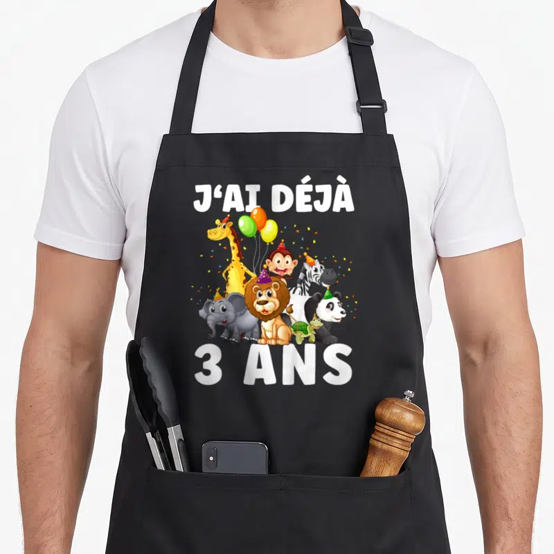 Tablier de cuisine noir avec l'inscription J'ai déjà 3 ans entourée d'animaux de zoo festifs et de ballons colorés.