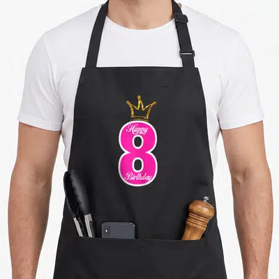 Tablier de cuisine noir avec un grand 8 rose vif surmonté d'une couronne dorée et du texte Happy anniversaire en blanc.