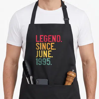 Tablier de cuisine noir avec inscription colorée Legend Since June 1995 en typographie vintage dégradée.