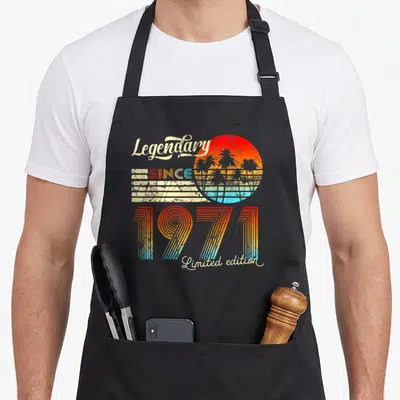 Tablier de cuisine noir avec illustration rétro « Legendary Since 1971 Limited edition » et soleil couchant aux palmiers.