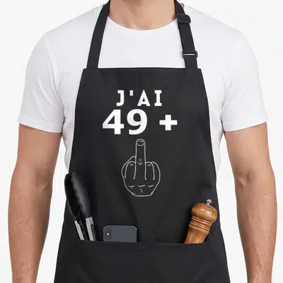 Tablier de cuisine noir avec inscription J'ai 49 + 1 et illustration de main levée en blanc.