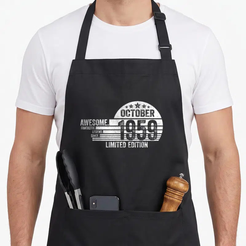 Tablier de cuisine noir avec inscription « Génial Octobre 1959 » et étoiles en blanc.