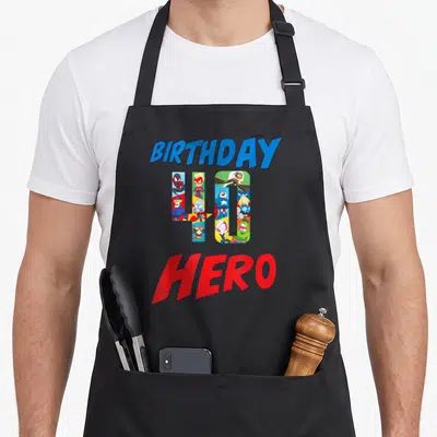Tablier de cuisine noir avec l'inscription anniversaire Hero 40 et des personnages de comics dans les chiffres.