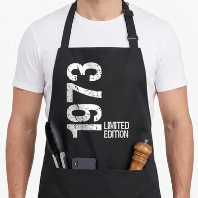 Tablier de cuisine noir avec l'année 1973 en gros chiffres blancs verticaux et Limited Edition à côté.