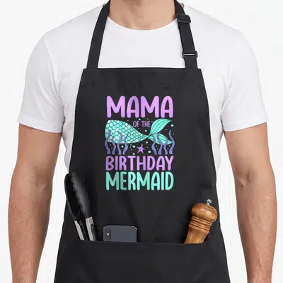 Tablier de cuisine noir avec motif sirène turquoise et texte MAMA OF THE anniversaire MERMAID en violet.