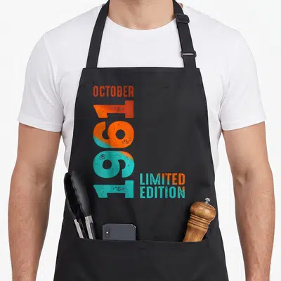 Tablier de cuisine noir avec l'inscription verticale Octobre 1961 Limited Edition en orange et turquoise.