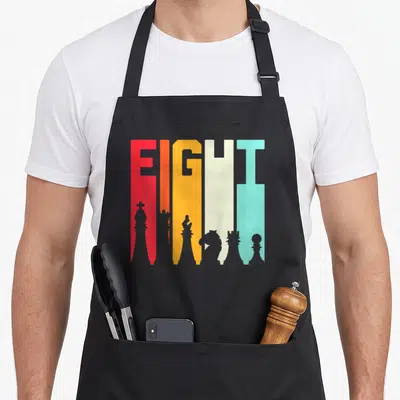 Tablier de cuisine noir avec le mot Fight et des pièces d'échecs stylisées en couleurs vives.