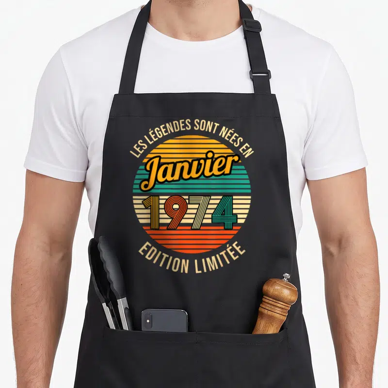 Tablier de cuisine noir avec motif circulaire rétro coloré et texte Les Légendes sont nées en Janvier 1974 « Édition Limitée ».
