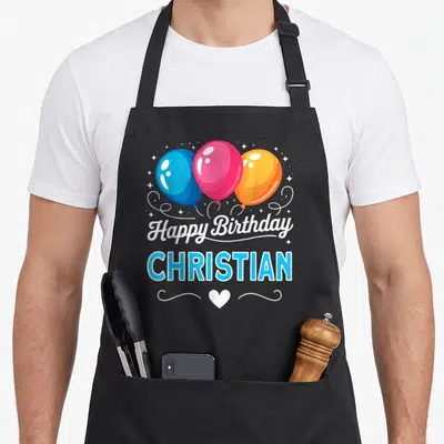 Tablier de cuisine noir avec Happy anniversaire Christian et trois ballons bleu rose orange entourés d'étoiles et d'un cœur blanc.