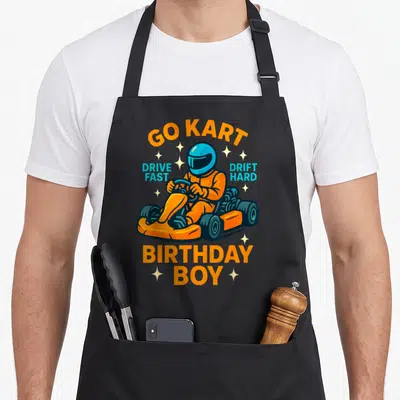 Tablier de cuisine noir avec un pilote de kart orange portant un casque bleu et les textes Go Kart anniversaire Boy Drive Fast Drift Hard.