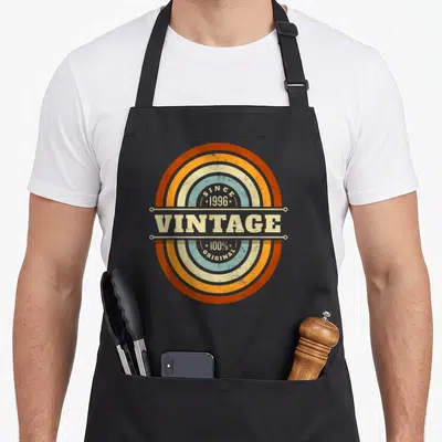 Tablier de cuisine noir avec logo circulaire vintageSince 1996 et 100% original en orange et bleu pastel.
