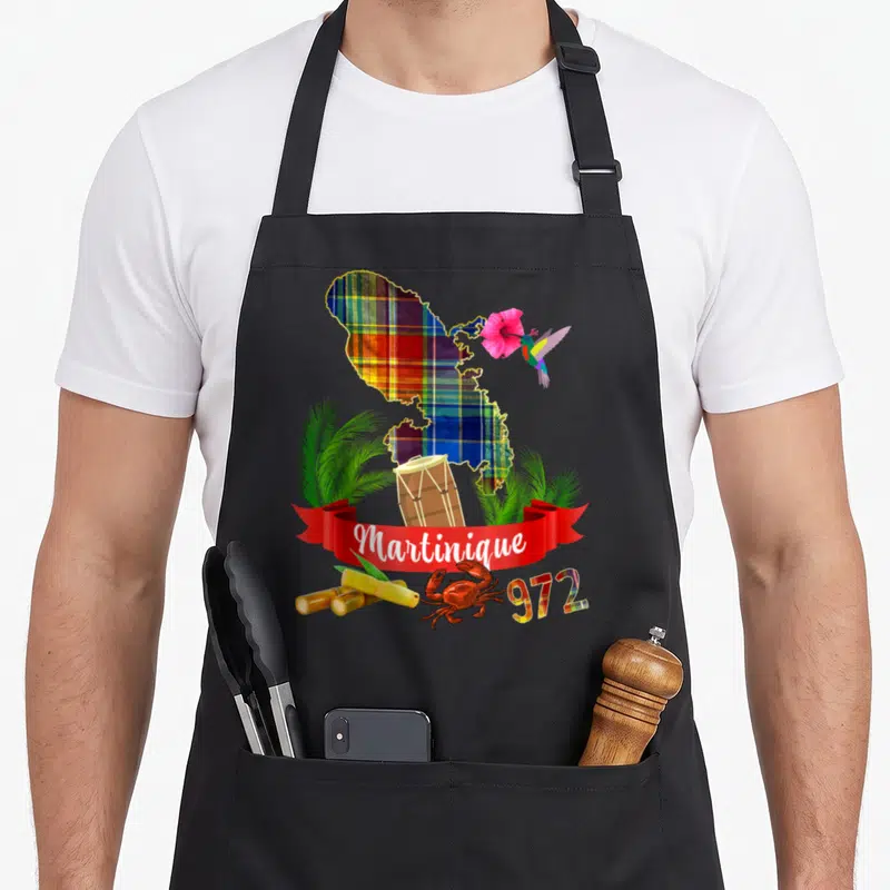 Tablier de cuisine noir avec carte Martinique Madras, hibou, fleur d'hibiscus, tambour, cannes à sucre et crabe sur bandeau rouge.