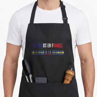 Tablier de cuisine noir avec inscription Les pieds en France le cœur à la Réunion et drapeau coloré.