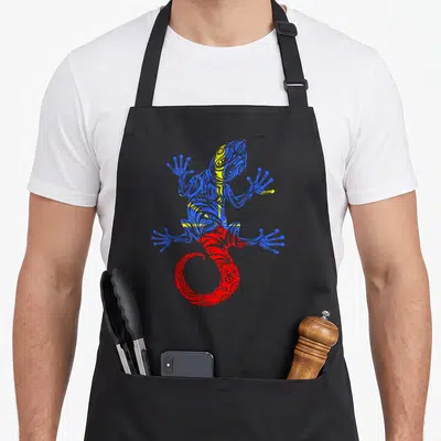 Tablier de cuisine noir avec un gécko stylisé aux motifs tribaux bleus jaunes et rouges représentant l'île de la Réunion.