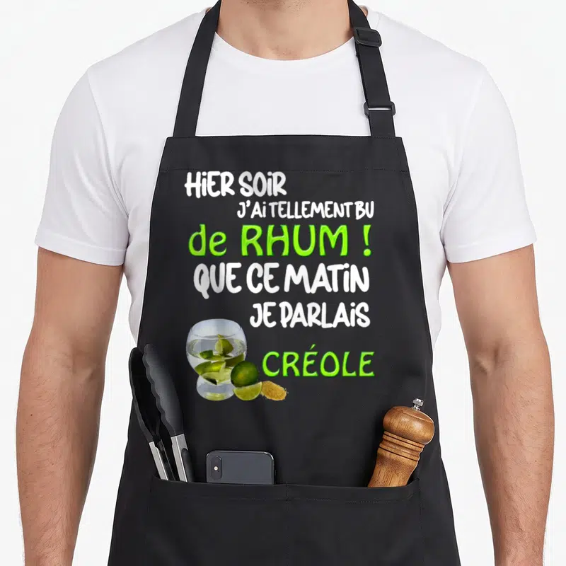 Tablier de cuisine noir avec texte blanc et vert sur le rhum et un verre à cocktail garni de citron vert.