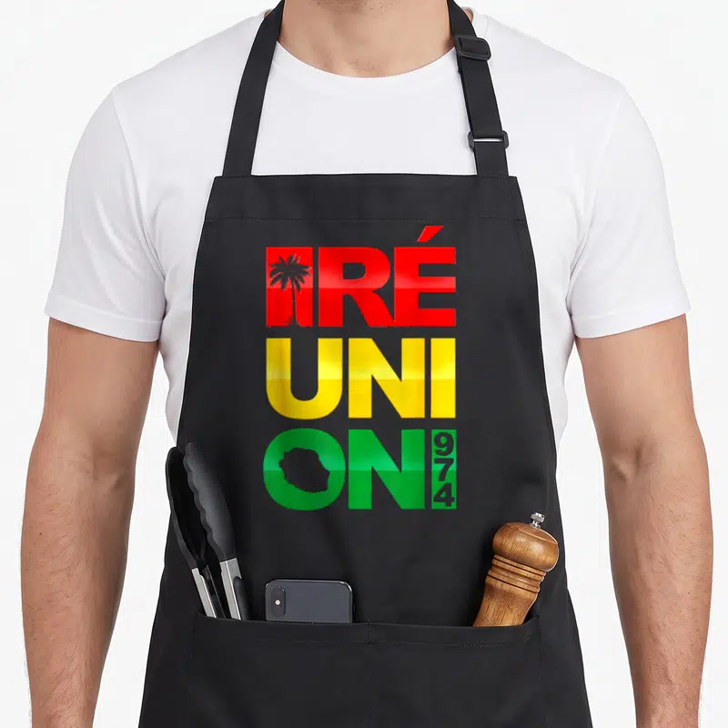 Tablier de cuisine noir avec inscription Réunion 974 aux couleurs rasta, palmier et silhouette de l'île insérés dans les lettres.