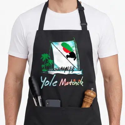 Tablier de cuisine noir avec une illustration de yole et le drapeau de la Martinique sur la voile.