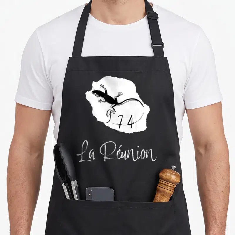 Tablier de cuisine noir avec carte blanche de La Réunion, un gécko noir et le numéro 974 stylisé.