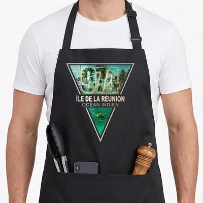 Tablier de cuisine noir avec motif géométrique représentant les palmiers et la tortue de l'île de la Réunion.