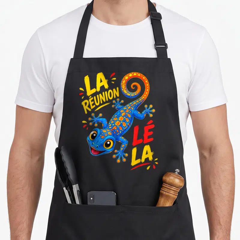 Tablier de cuisine noir avec un lézard bleu orné de taches orange et le texte La Réunion Lé La en lettres vives.