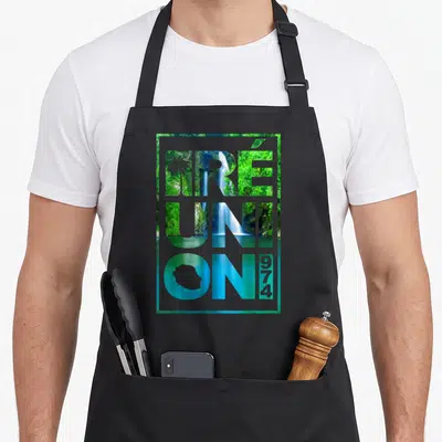 Tablier de cuisine noir avec le mot Réunion et une illustration de cascade tropicale en arrière-plan.