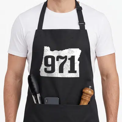 Tablier de cuisine noir avec carte blanche de l'Oregon et le chiffre 971 en gris délavé au centre.