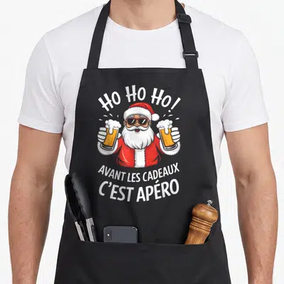 Tablier de cuisine noir avec un Père Noël en lunettes de soleil tenant deux bières et le texte Avant les cadeaux c'est apéro.