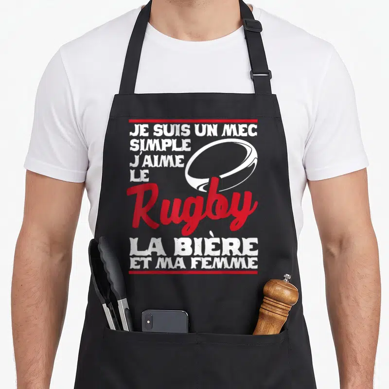 Tablier de cuisine noir avec inscription blanche et rouge sur le rugby et la bière, illustré d'un ballon ovale.