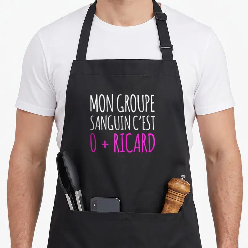 Tablier de cuisine noir avec l'inscription Mon groupe sanguin c'est 0 plus Ricard en blanc et rose vif.