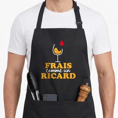 Tablier de cuisine noir avec illustration de verre jaune et texte frais comme un Ricard en orange et blanc.