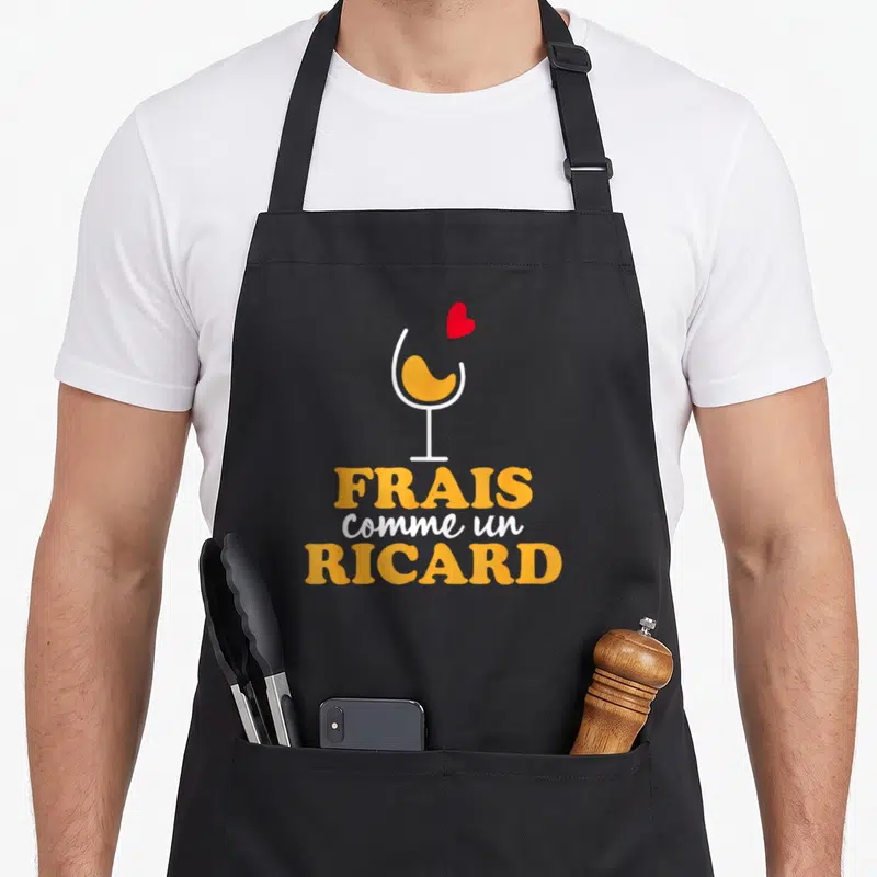 Tablier de cuisine noir avec illustration de verre jaune et texte frais comme un Ricard en orange et blanc.