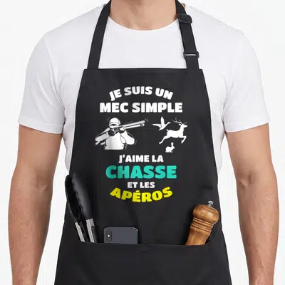 Tablier de cuisine noir avec un chasseur au fusil, un cerf, un canard et un lapin blancs accompagnés du texte Je Suis Un Mec Simple Chasse Apéros.