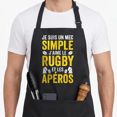 Tablier de cuisine noir avec inscription jaune et blanche sur le rugby et les apéros, orné de ballons et de verres de bière.