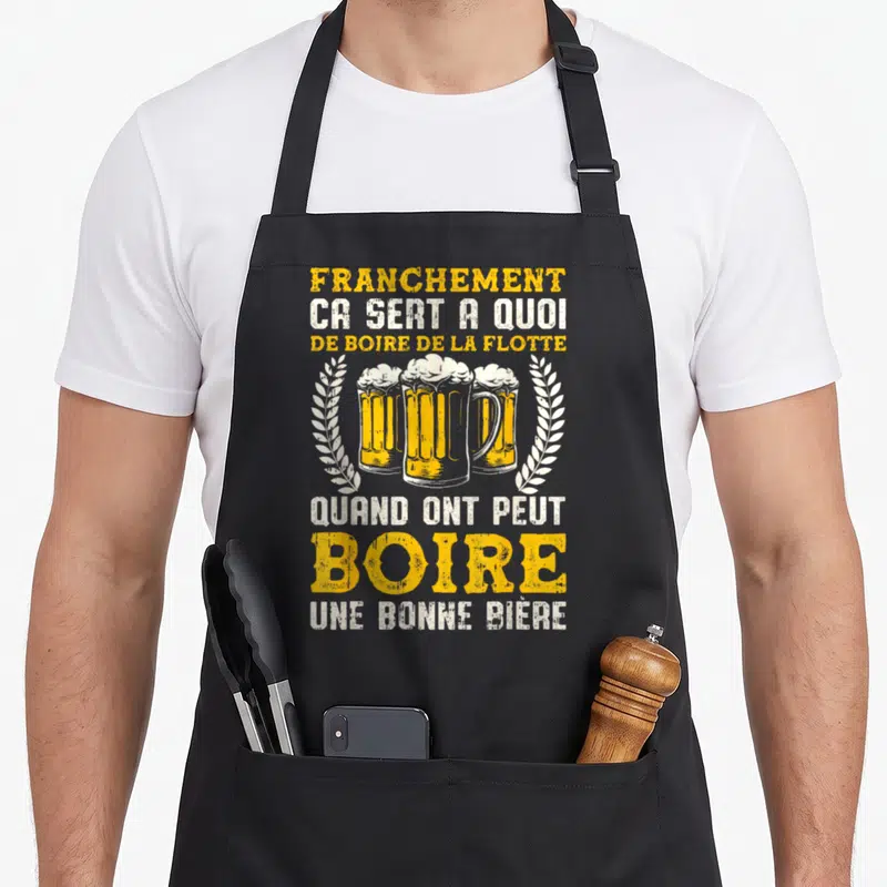 Tablier de cuisine noir avec trois verres de bière jaunes encadrés de couronnes blanches et texte humoristique sur l'apéro.