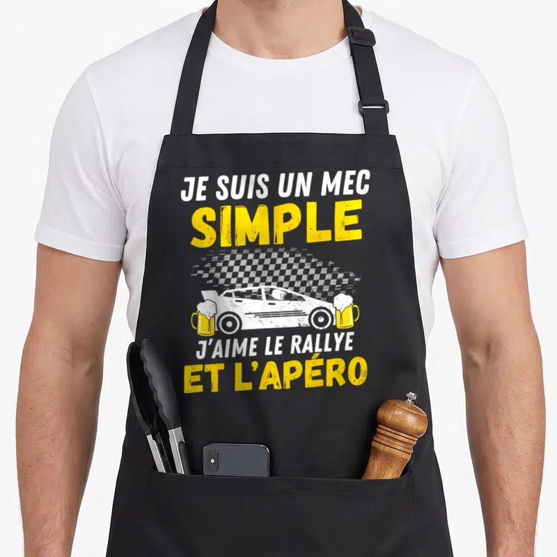 Tablier de cuisine noir avec illustration de voiture de rallye, deux verres de bière et texte blanc et jaune sur fond gris.