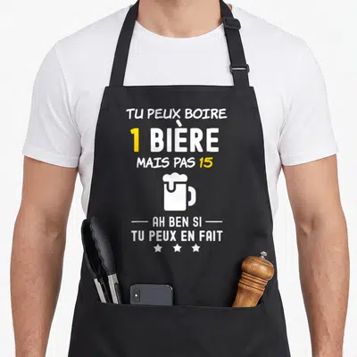 Tablier de cuisine noir avec inscription blanche et jaune sur l'apéro et une illustration de mug de bière.