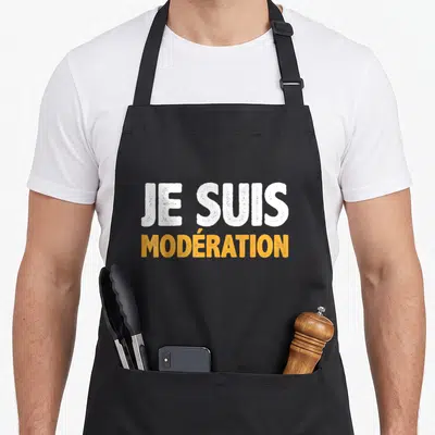 Tablier de cuisine noir avec l'inscription Je Suis Modération en blanc et orange sur le devant.
