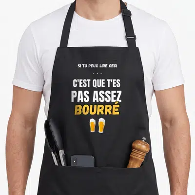 Tablier de cuisine noir avec inscription blanche et jaune Si tu peux lire ceci c'est que t'es pas assez bourré surplombant deux verres de bière.