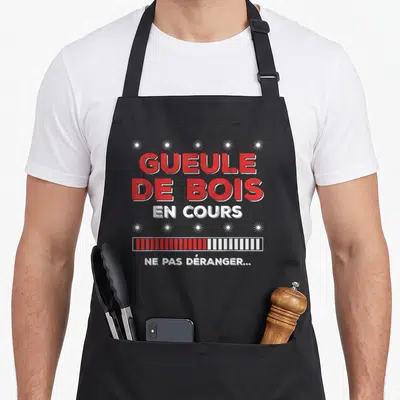 Tablier de cuisine noir avec inscription rouge GUEULE DE BOIS EN COURS et barre de chargement stylisée.