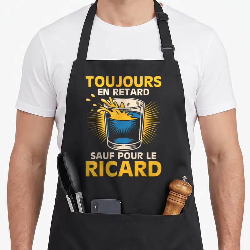 Tablier de cuisine noir avec illustration d'un verre de pastis éclaboussant et texte jaune blanc