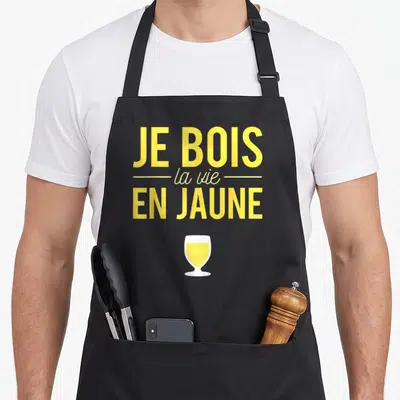 Tablier de cuisine noir avec inscription Je bois la vie en jaune et illustration de verre de pastis jaune.