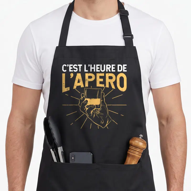 Tablier de cuisine noir avec une illustration jaune représentant une main tenant un verre sous le texte C'est l'heure de l'apéro.
