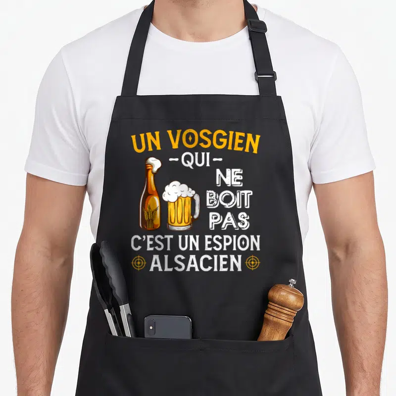 Tablier de cuisine noir avec une bière et le texte Un Vosgien qui ne boit pas c'est un espion alsacien en orange et blanc.