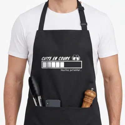 Tablier de cuisine noir avec texte blanc Cuite en cours, barre de chargement et deux bières qui se touchent.