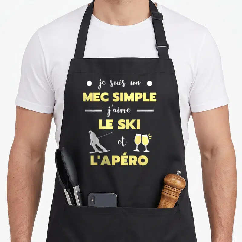 Tablier de cuisine noir avec texte jaune blanc et silhouettes skieur et verres à champagne