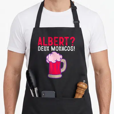 Tablier de cuisine noir avec l'inscription Albert deux Monacos et une grande bière rose sur le devant.