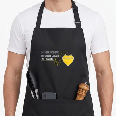 Tablier de cuisine noir avec inscription En cas de problème mon groupe sanguin O+ Pastis et illustration sac de sang jaune.